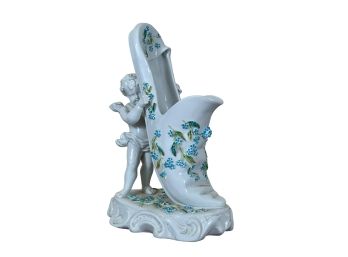 PORCELAIN SHOE HELD UP BY CHERUB